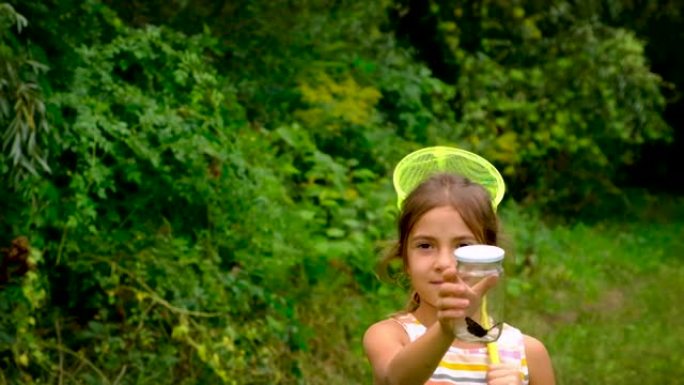 一个小女孩用蝴蝶网捉蝴蝶。选择性聚焦。自然。