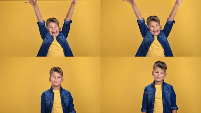 肖像喜出望外的快乐男孩孩子欢欣鼓舞赢得胜利，举起双手孤立在橙色上