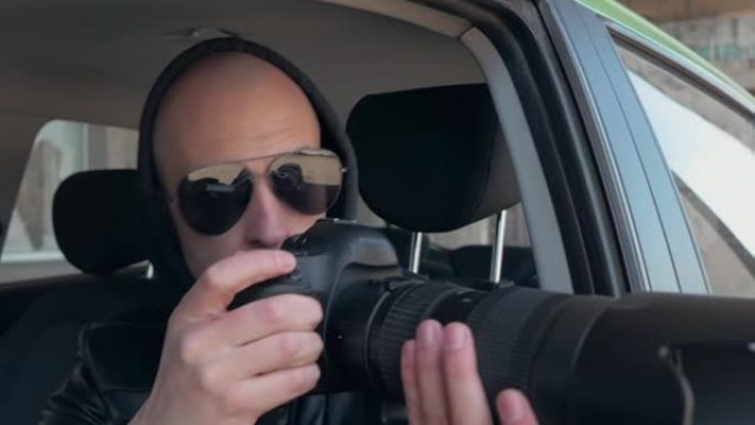 一名男子坐在汽车上，用专业相机，私人侦探或狗仔队间谍拍照。