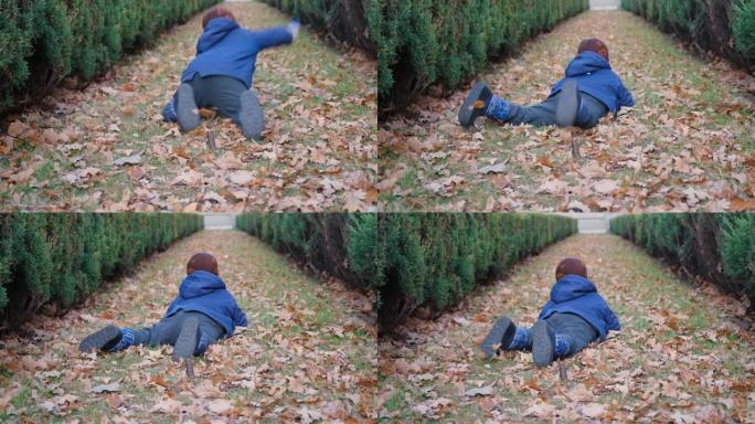 一个4岁的孩子在秋天的树叶中奔跑并跌倒。