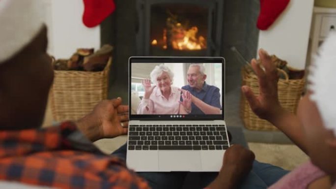 戴着圣诞老人帽子的非洲裔美国夫妇使用笔记本电脑进行圣诞视频通话，屏幕上有夫妇