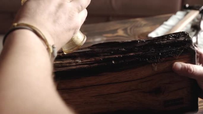 用海绵在木橡木板上涂抹木材用油。木材浸渍和木油的应用。木工概念。在木托盘上涂上木油