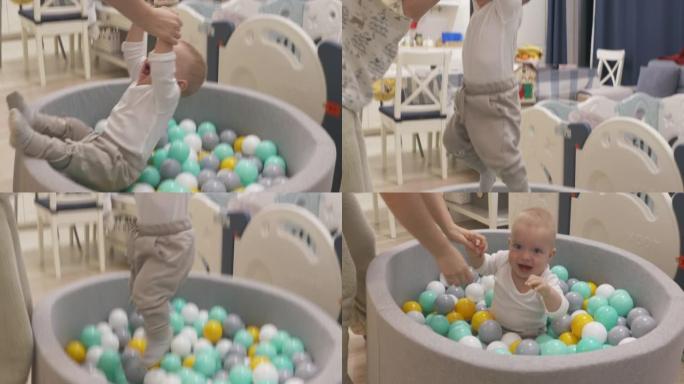 妈妈和快乐的宝宝在软球坑池玩五颜六色的球，9个月大的高加索孩子在儿童干池微笑，玩有趣的游戏。