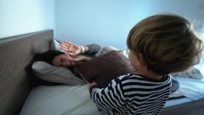 蹒跚学步的孩子早上和妈妈打枕头，用枕头叫醒父母