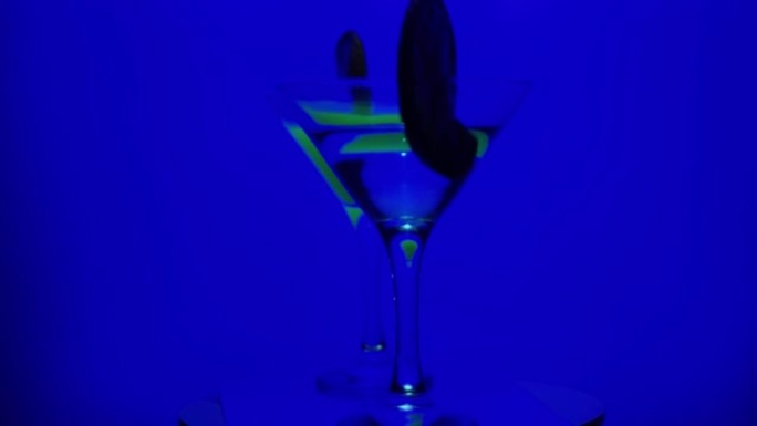带有鸡尾酒的迷人眼镜在霓虹灯的吧台上旋转