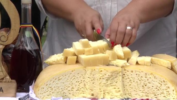 红色指甲的女人用小刀切开小奶酪块，将其放在另一位女士从中品尝并品尝72的流行毛巾上
