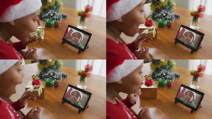 戴着圣诞老人帽子的非洲裔美国妇女使用平板电脑与屏幕上的男孩进行圣诞节视频通话