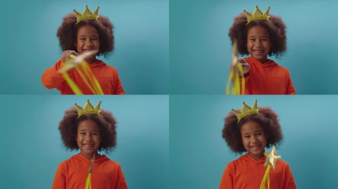 戴着皇冠的可爱的非洲裔美国女孩拿着魔杖看着相机。微笑的女孩扮演仙女。让魔法开始。