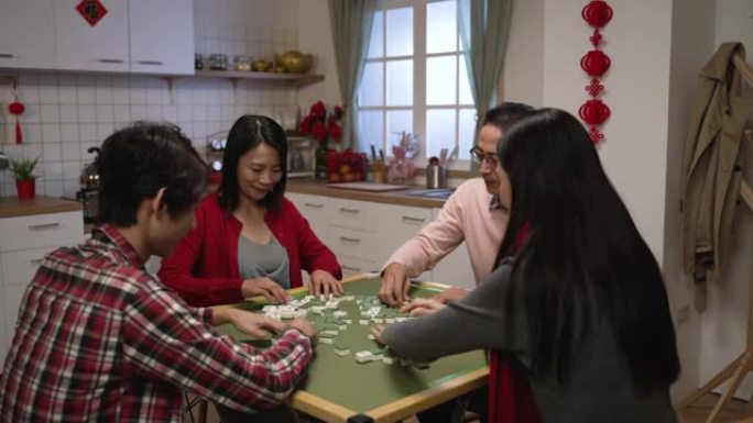 亚洲四口之家在除夕夜一起打麻将时，在家里洗牌。中文背景翻译:运气