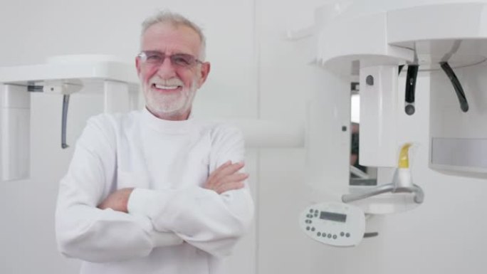 一位穿着白大褂的面带微笑的高级首席医生以特写镜头看着镜头。在x光室里，一位自信、熟练、快乐的全科医生