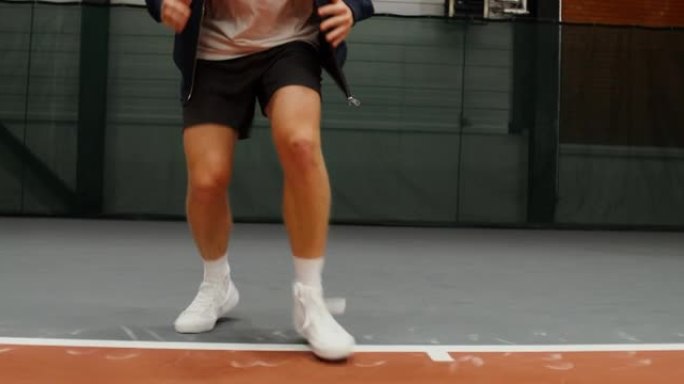 一名年轻人在室内网球场打网球前进行热身