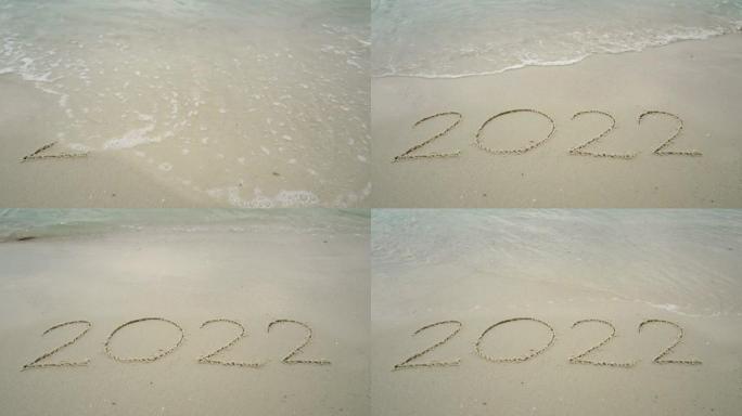 4k快乐新2022年。数字2021写在沙滩上，海浪飞溅变化2022年。新年快乐倒计时从2021年20