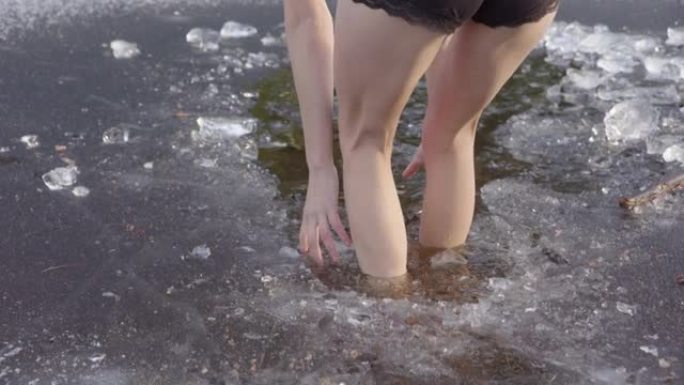 一个年轻女子的美丽腿走进冰冷的水中，跳了出来