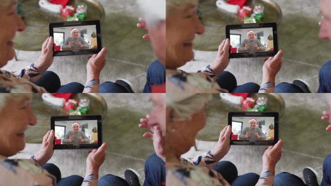 高级高加索夫妇使用平板电脑与屏幕上的快乐男人进行圣诞节视频通话