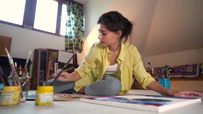 坐在地板上，女艺术家在画布上绘画