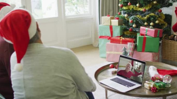 多元化的资深女性朋友挥舞并使用笔记本电脑与屏幕上的男人进行圣诞节视频通话