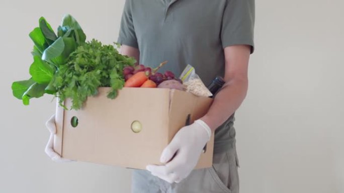 男子戴着手套和口罩回家运送食品盒，志愿者拿着食品盒进行捐赠概念