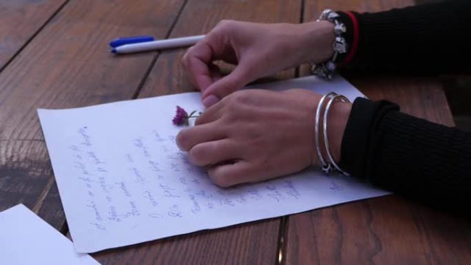 一个手腕上戴着银手镯的女人的手在给男友的信中缺少三叶草花83