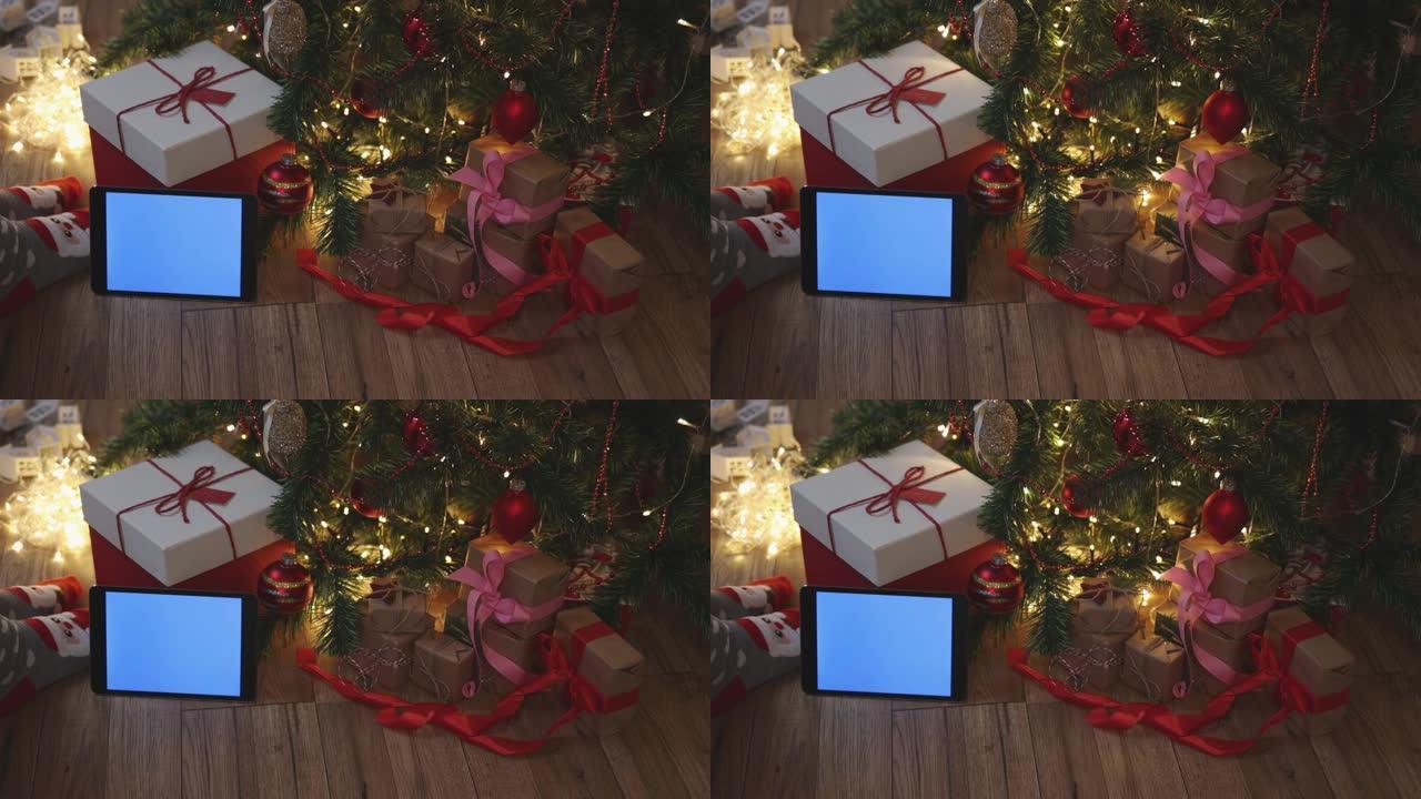 枞树下的圣诞红色工艺礼品盒和平板蓝色模型屏幕