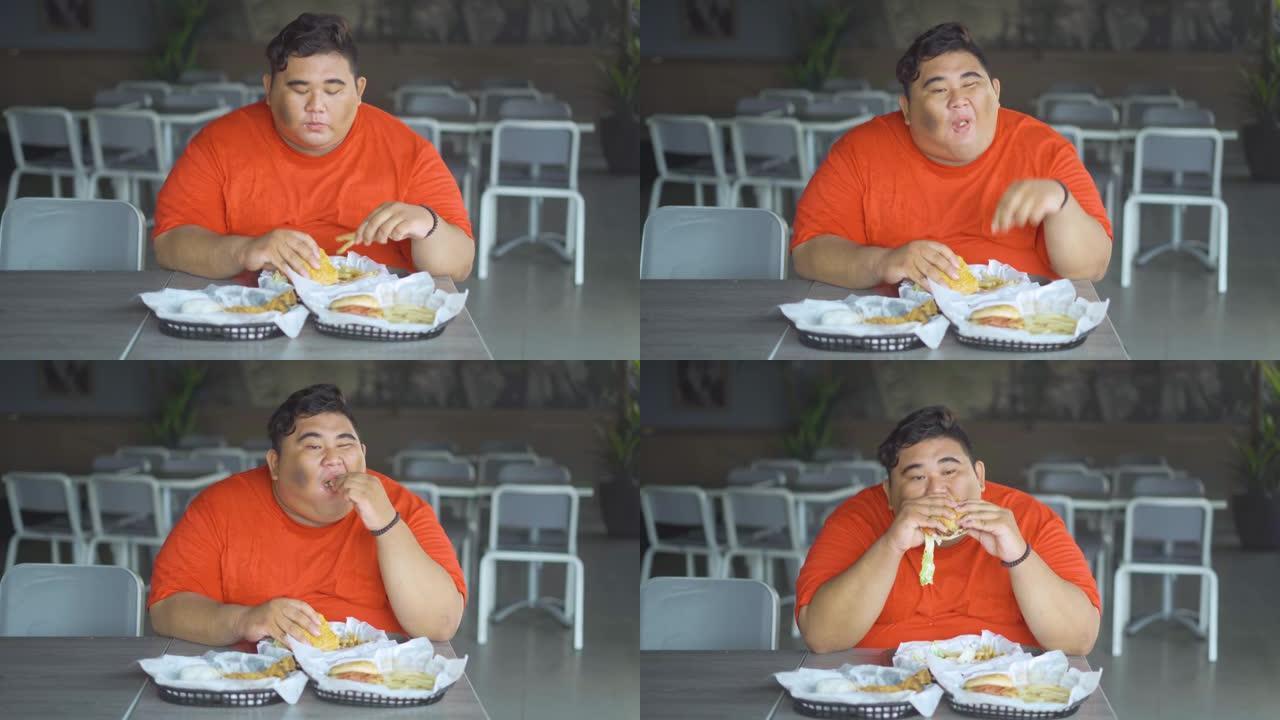 贪婪的肥胖男子吃汉堡和炸薯条