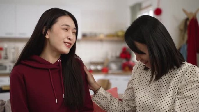 春节在家收红包时，身着红色衣服的亚洲女儿微笑着拥抱母亲的特写