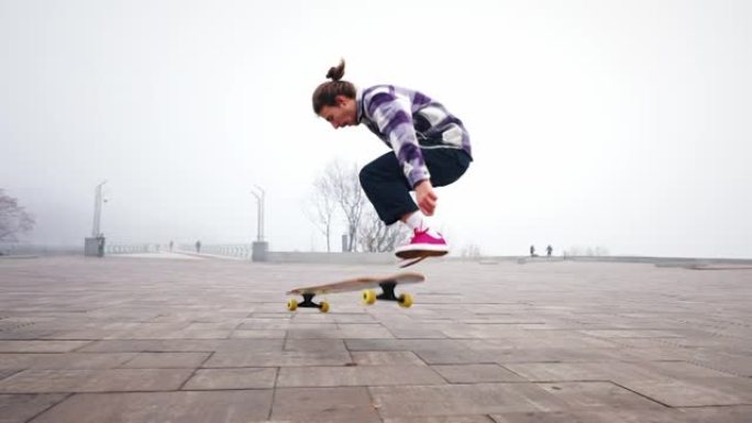 这家伙正在城市公园里骑长板。自由式滑板风格。在空中跳跃和翻转溜冰鞋。用手保持平衡。慢动作，子弹时间