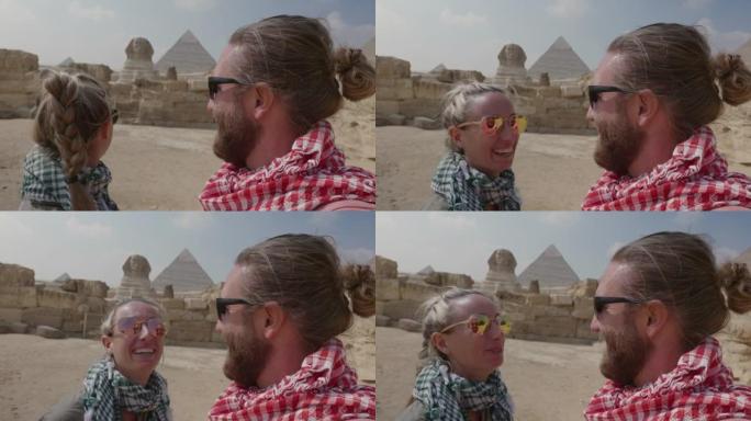 在埃及旅行的年轻夫妇正在考虑大金字塔。开罗的夫妇旅行者观光金字塔和著名的狮身人面像