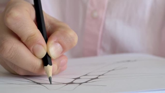 用手指拿着黑色铅笔在纸上画线的特写手为未来的创作艺术和绘画准备素描