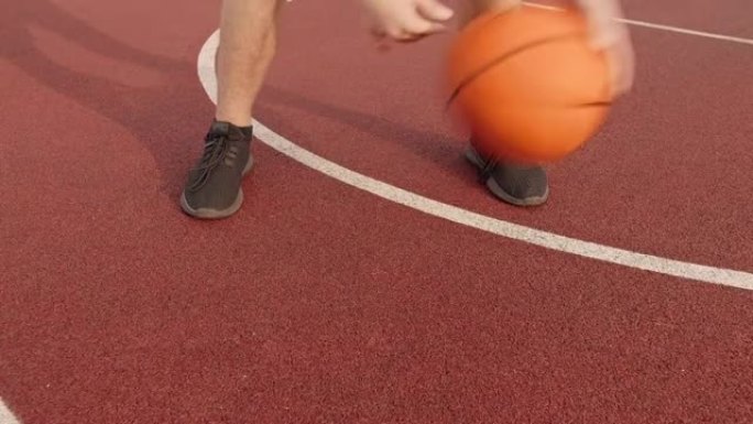 腿部男子通过在室外球场上两腿之间滚动篮球来练习球技