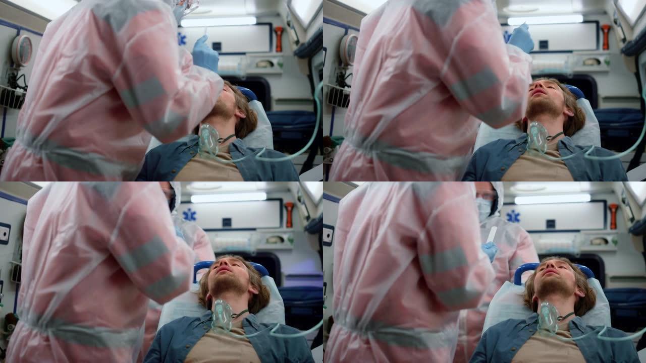 医护人员小组对紧急车辆中的男子冠状病毒进行鼻拭子测试