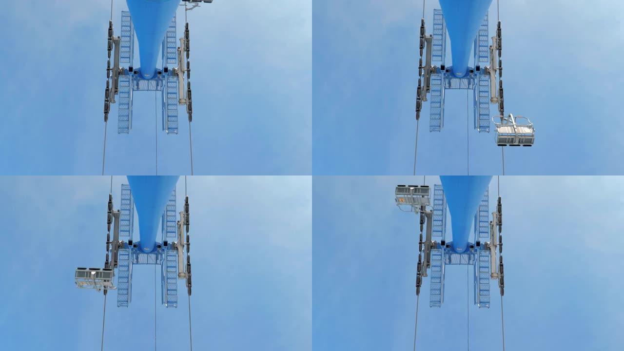 冬季在蓝天下从滑雪缆车吊塔下方观看