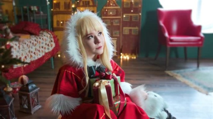 可爱的女孩角色扮演圣诞米库圣诞老人礼服与礼物。新年精灵。坐在地板上