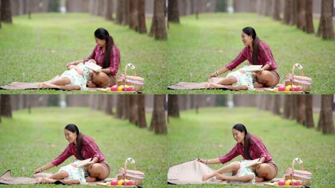 在松园和妈妈一起读小说的女孩。在阳光明媚的夏日，女孩们坐在松树下。