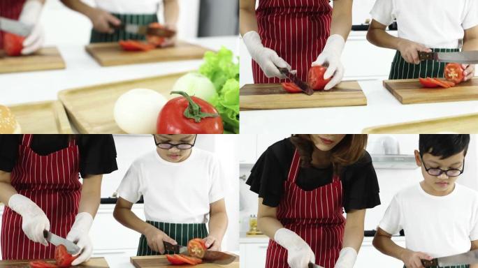 可爱的母亲教年轻的小儿子如何在现代白色调厨房切西红柿做汉堡。家庭中爱与关系的概念。