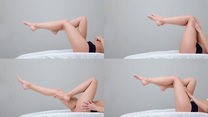 苗条性感的女人躺在床上，抬起优雅光滑的双腿。副本的空间。脱毛和脱毛的概念