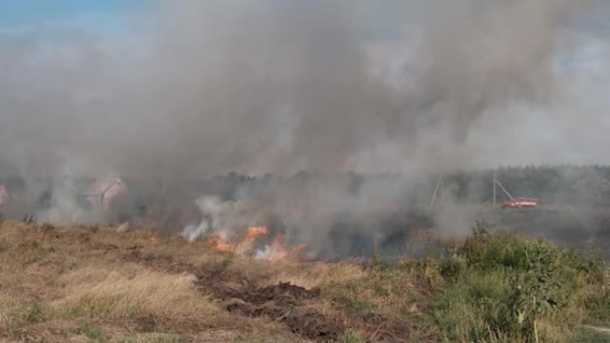 夏天在村庄附近的田野里烧干草，拖拉机扑灭了大火