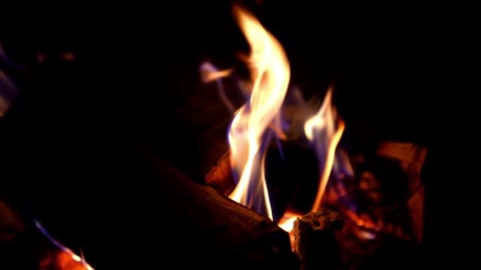 壁炉里温暖舒适的燃烧之火。黑色背景上燃烧的火和火焰。火焰和燃烧的火花。火势。黑暗中的火光与复制空间。