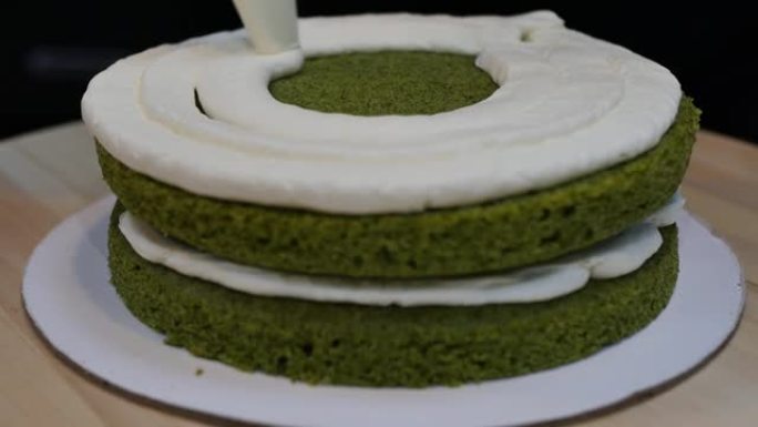 在菠菜海绵绿色蛋糕上涂一层厚厚的奶油