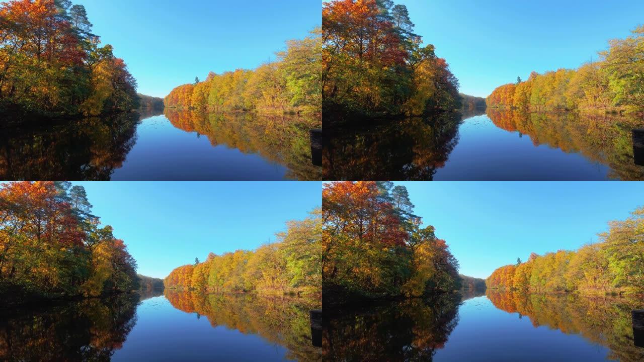 平静的湖泊，岸边有秋天的彩色树木，映在微动的水中