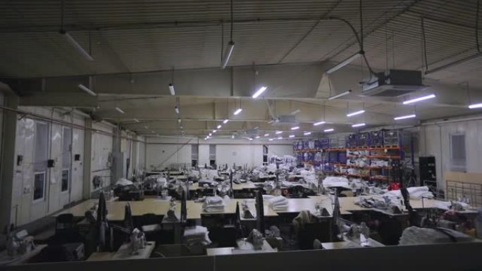 关掉一家大型服装厂的灯。在制衣厂的车间里的工作日结束。关掉工厂的灯。