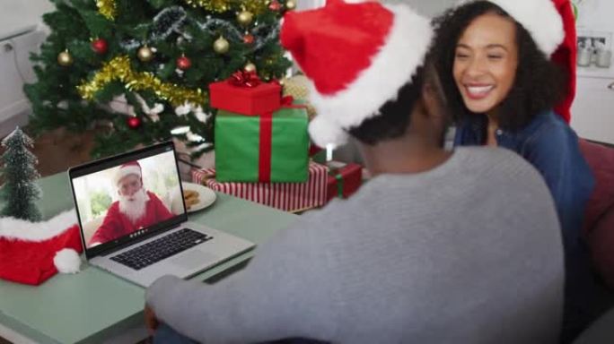 圣诞节时，与圣诞老人一起在笔记本电脑上视频通话的快乐非洲裔美国夫妇