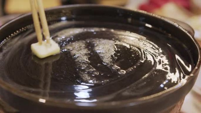 正面视图，用筷子把黄油涂在锅上。