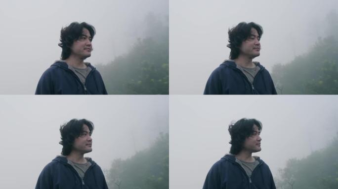 男性旅行者在清晨的背景中欣赏山顶的景色，浓雾。度假的生活方式。