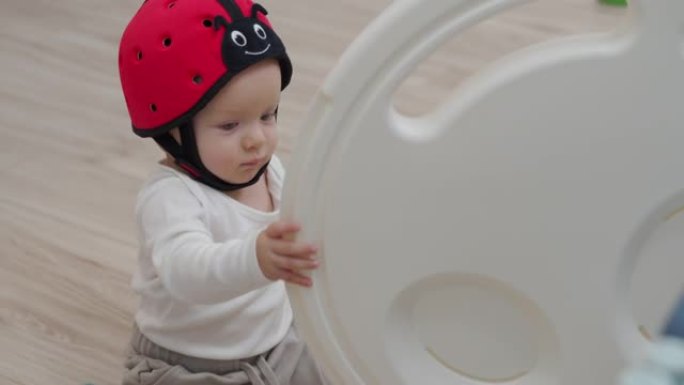 可爱的幼儿宝宝玩儿童活动中心游戏场的门，活跃的孩子戴着婴儿安全帽。