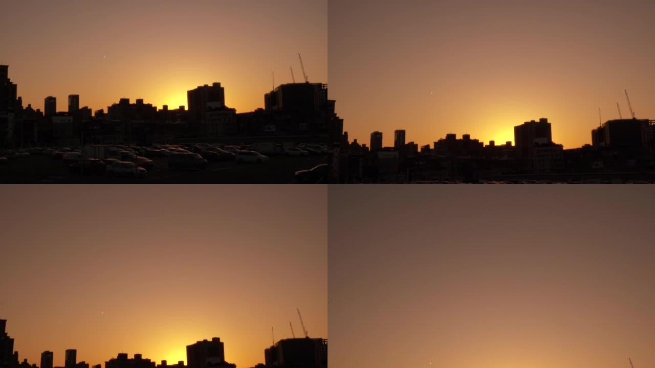 日落风景与城市的建筑轮廓。焦点在正面，背景模糊。镜头轻微晃动。天空的色温是黄色的。