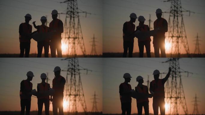 电网建设专家团队正在讨论发电厂背景和日落，剪影的电塔项目