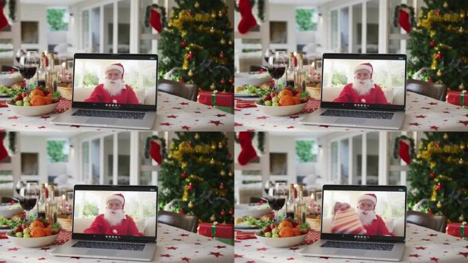 快乐的高加索圣诞老人躺在圣诞桌上的笔记本电脑上
