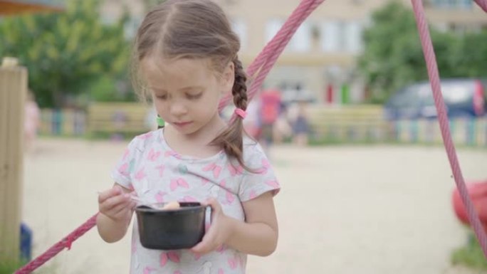 小女孩吃冰激凌勺子户外游乐场塑料板夏日慢动作