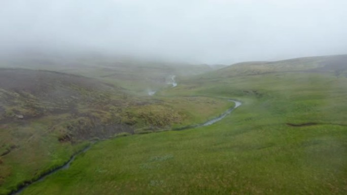 雾天雷克雅达勒温泉河泳池山谷鸟瞰。冰岛绿色乡村地热河流流动的雾状无人机视图