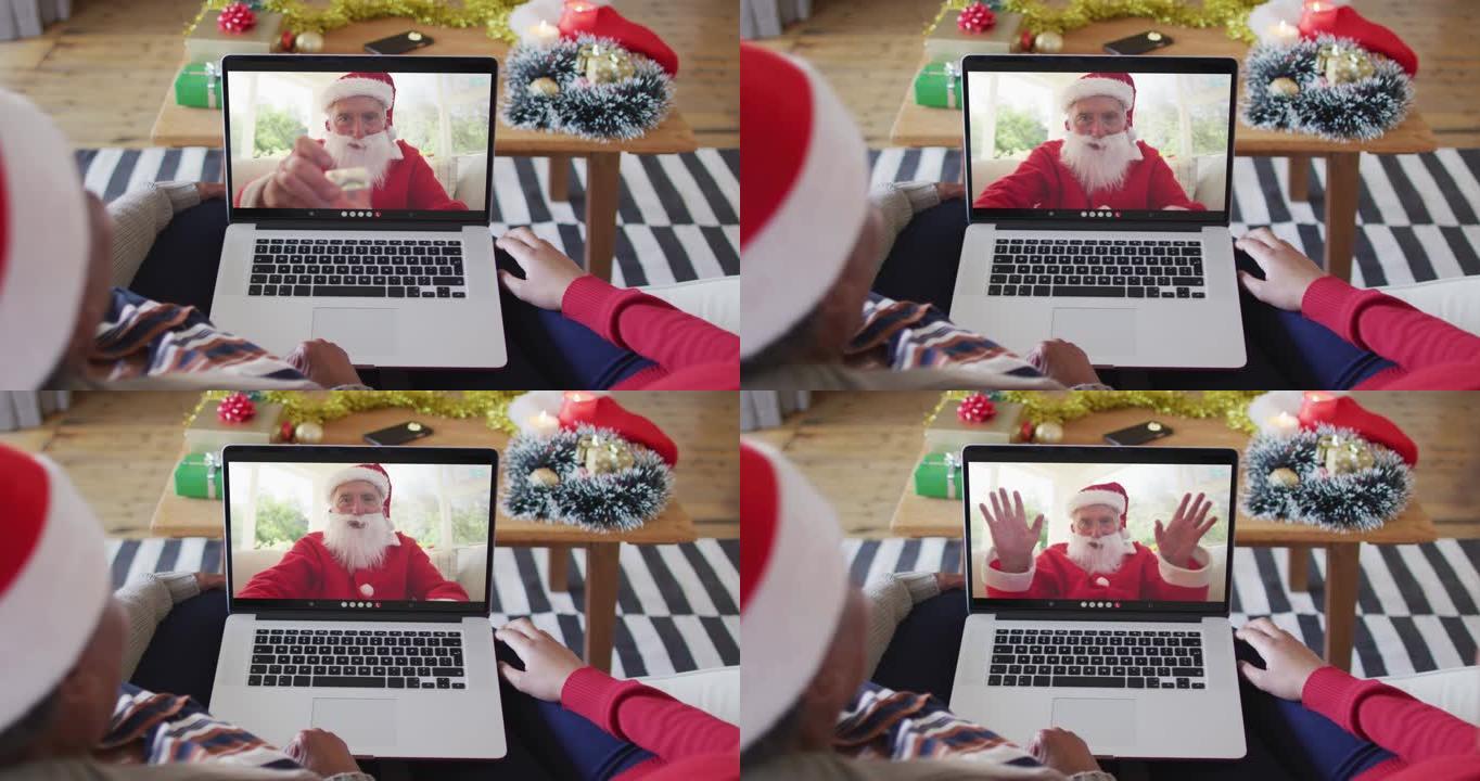非裔美国母亲和女儿使用笔记本电脑与屏幕上的圣诞老人进行圣诞节视频通话